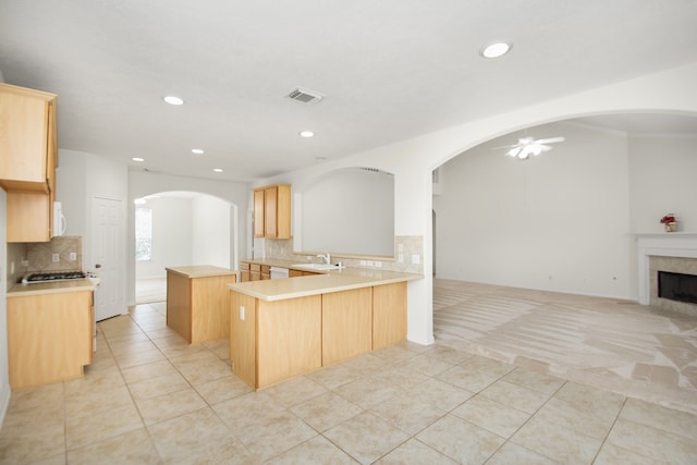 kitchen with decorative backsplash, kitchen peninsula, light brown cabinets, light tile patterned floors, and ceiling fan