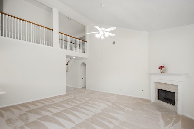 unfurnished living room with high vaulted ceiling, light colored carpet, ceiling fan, and a tile fireplace