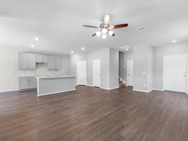 unfurnished living room with ceiling fan and dark wood-type flooring