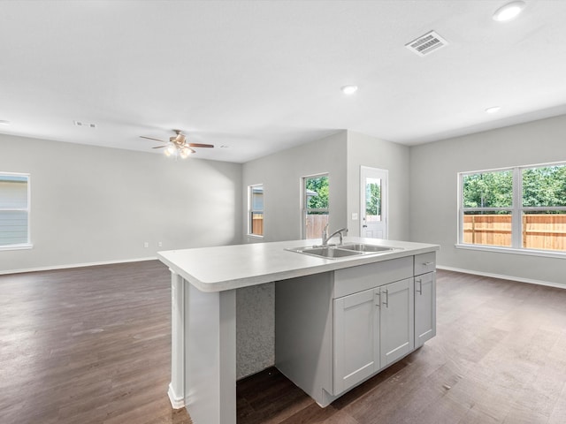 kitchen with an island with sink, white cabinets, dark hardwood / wood-style flooring, ceiling fan, and sink