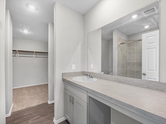 bathroom with a tile shower, vanity, and hardwood / wood-style flooring