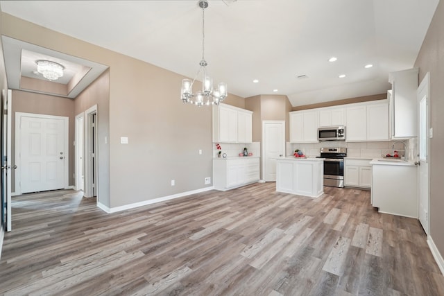 kitchen with light hardwood / wood-style flooring, stainless steel appliances, white cabinets, and an inviting chandelier