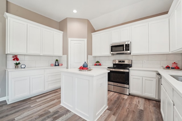 kitchen with white cabinetry, tasteful backsplash, stainless steel appliances, lofted ceiling, and light hardwood / wood-style flooring