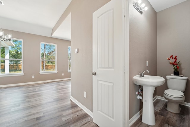 bathroom featuring wood-type flooring, toilet, and a notable chandelier