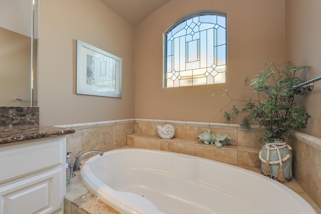 bathroom featuring a relaxing tiled tub and vanity