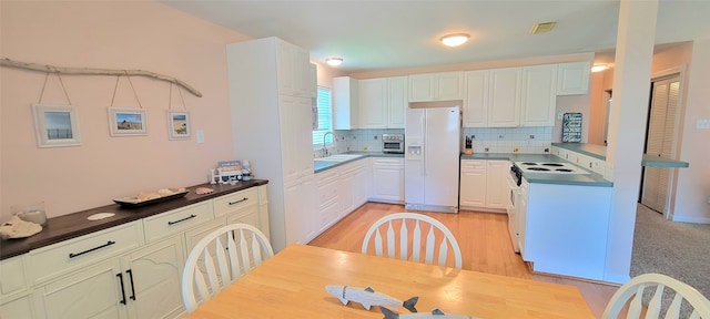 kitchen with white cabinets, sink, white appliances, light wood-type flooring, and decorative backsplash