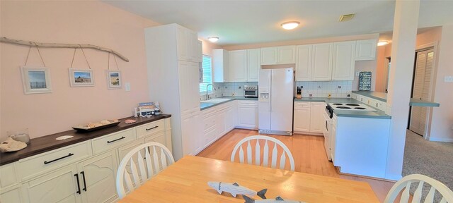 4015 Navarro Dr, Galveston, TX 77554 - kitchen with white cabinets, tasteful backsplash, light wood-type flooring, visible vents, and white appliances