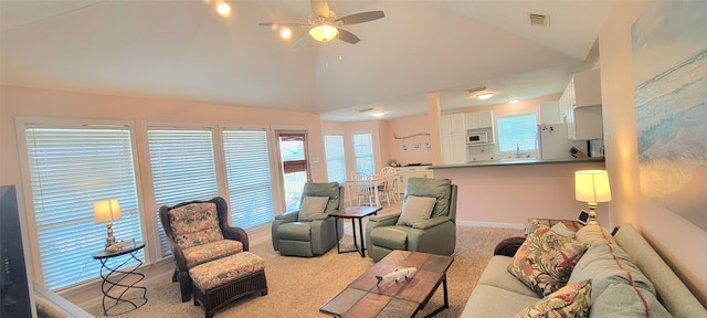 carpeted living room with ceiling fan and high vaulted ceiling