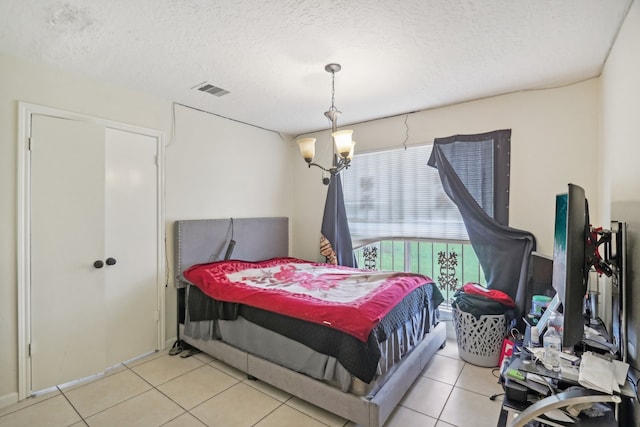 tiled bedroom with a chandelier and a textured ceiling