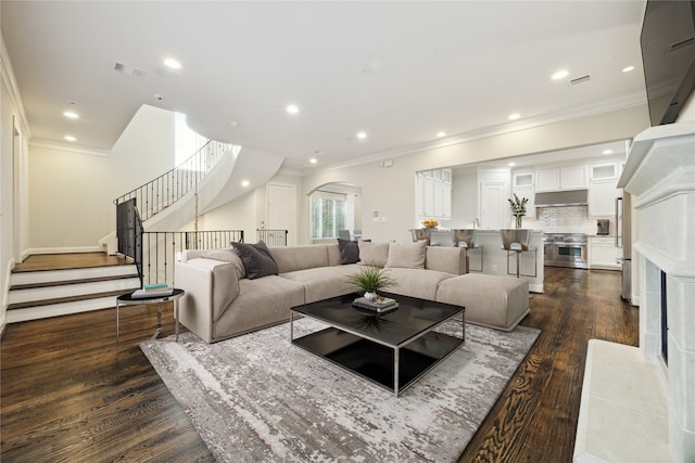 living room featuring a premium fireplace, dark hardwood / wood-style floors, and crown molding