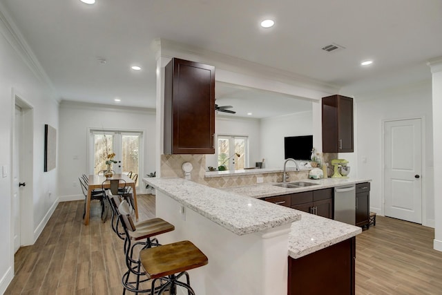 kitchen with sink, ceiling fan, ornamental molding, a kitchen bar, and kitchen peninsula