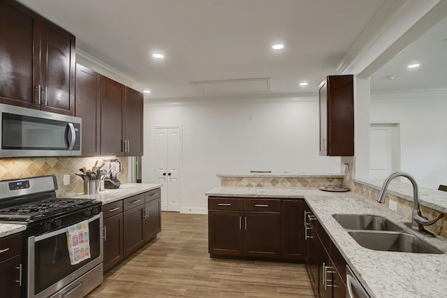 kitchen with light stone countertops, sink, stainless steel appliances, and ornamental molding