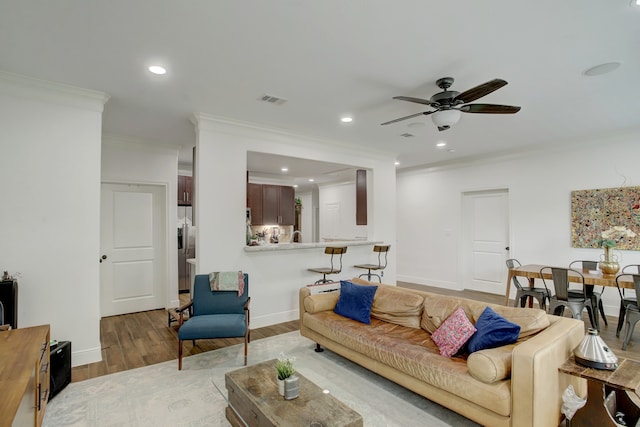 living room with ceiling fan, wood-type flooring, and ornamental molding