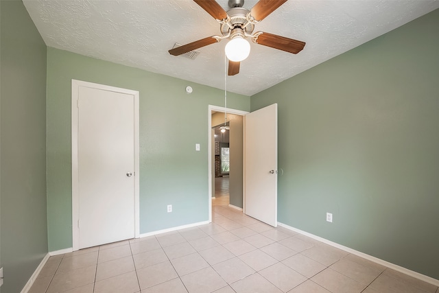 unfurnished bedroom featuring ceiling fan, light tile patterned flooring, and a textured ceiling