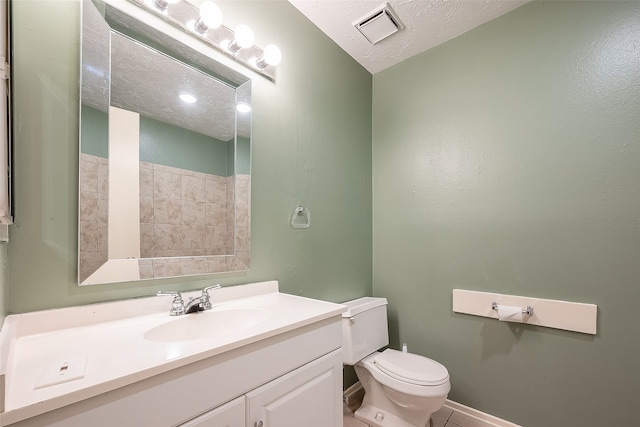 bathroom featuring a textured ceiling, tile patterned flooring, vanity, and toilet