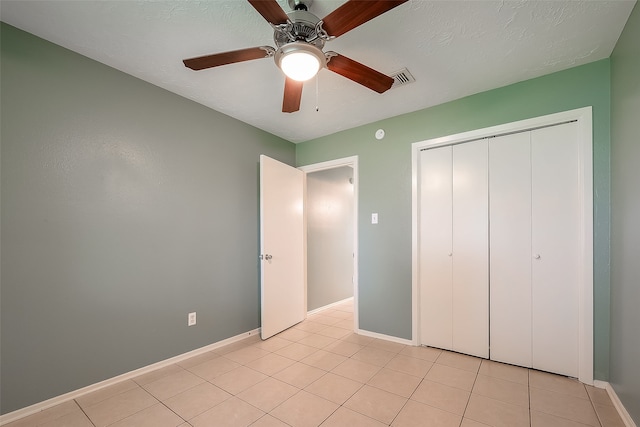 unfurnished bedroom featuring a closet, ceiling fan, light tile patterned flooring, and a textured ceiling