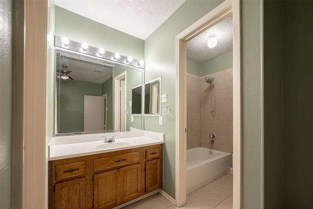 bathroom featuring ceiling fan, tiled shower / bath, vanity, a textured ceiling, and tile patterned flooring