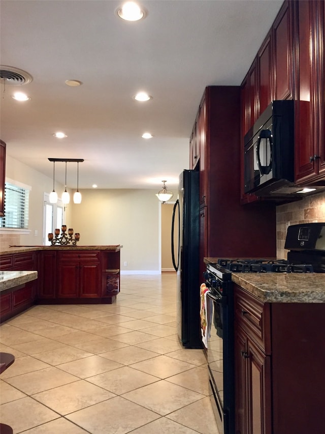 kitchen with dark stone countertops, hanging light fixtures, tasteful backsplash, and black appliances