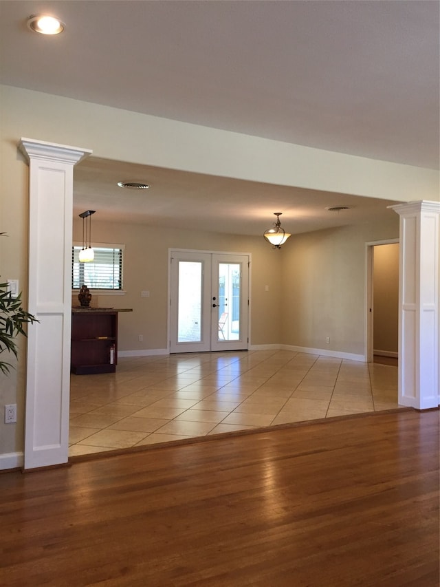 empty room with decorative columns, french doors, and hardwood / wood-style flooring