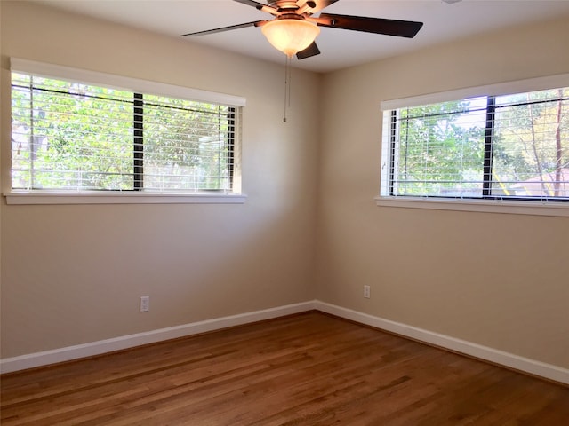 empty room featuring a healthy amount of sunlight, wood-type flooring, and ceiling fan