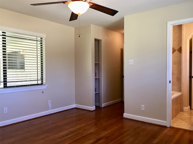 unfurnished bedroom with ceiling fan, ensuite bathroom, and dark wood-type flooring