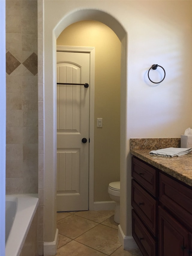 bathroom with a bathtub, vanity, toilet, and tile patterned floors