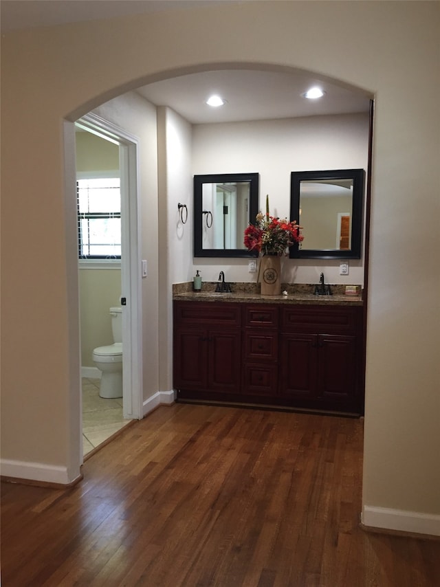 bathroom with wood-type flooring, vanity, and toilet