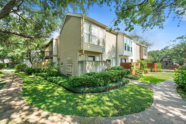 view of side of property with a balcony and a yard