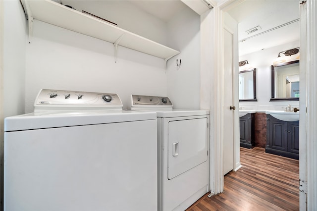 washroom with dark hardwood / wood-style flooring, washing machine and clothes dryer, and sink