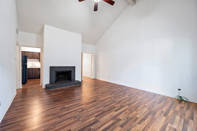 unfurnished living room with ceiling fan, beam ceiling, a brick fireplace, dark wood-type flooring, and high vaulted ceiling