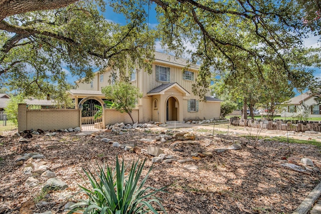 110 Monroe St, Giddings, TX 78942 - mediterranean / spanish home featuring brick siding, fence, a gate, and board and batten siding