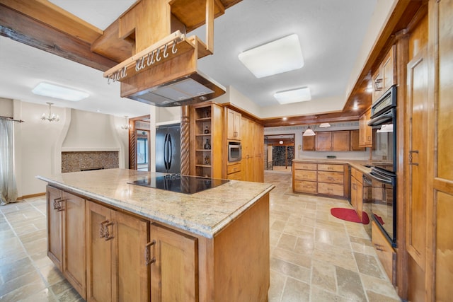 kitchen featuring pendant lighting, light stone countertops, a center island, and black appliances