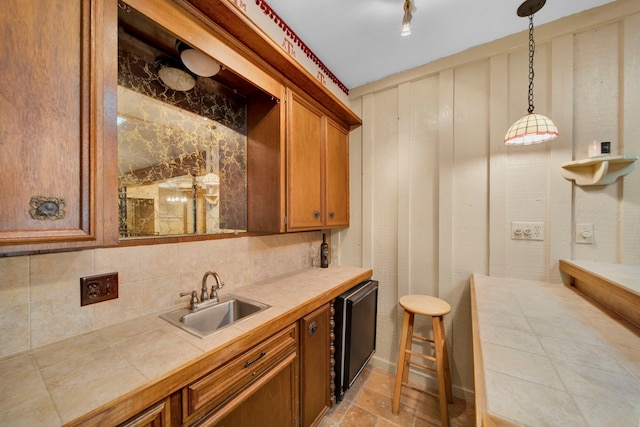 kitchen featuring tile countertops, hanging light fixtures, sink, and decorative backsplash