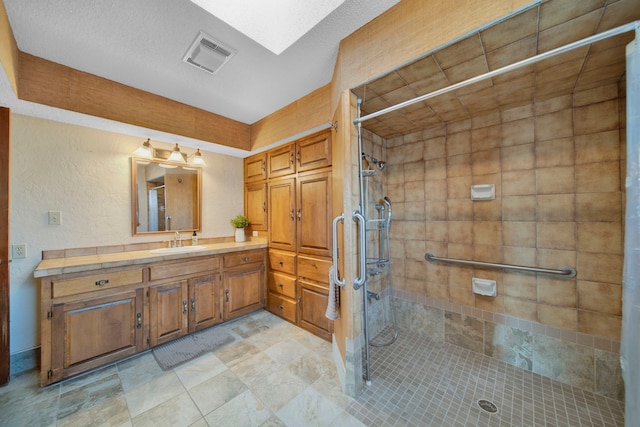 bathroom featuring a skylight, vanity, a textured ceiling, and an enclosed shower