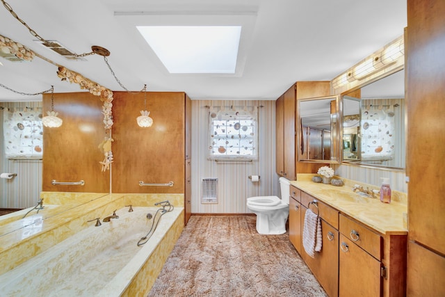 bathroom featuring heating unit, a bathtub, a skylight, vanity, and toilet