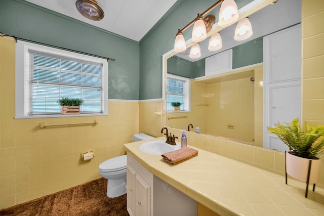 bathroom with tile walls, a healthy amount of sunlight, vanity, and toilet