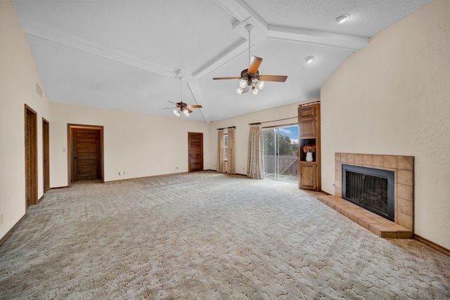 unfurnished living room with a tiled fireplace, beamed ceiling, a textured ceiling, ceiling fan, and light colored carpet