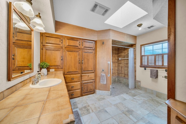 bathroom featuring a textured ceiling, vanity, curtained shower, and a skylight