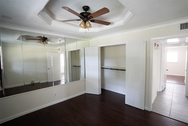 interior space with ornamental molding, dark wood-type flooring, a raised ceiling, and ceiling fan