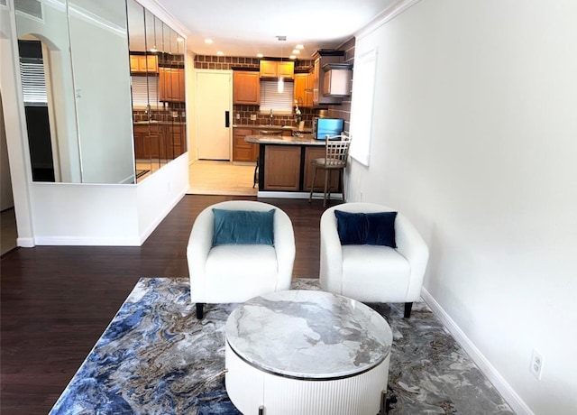 living area with ornamental molding, sink, and dark hardwood / wood-style floors