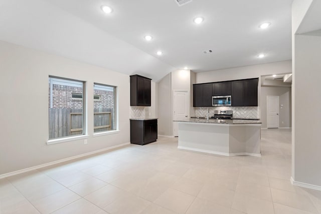 kitchen featuring tasteful backsplash, appliances with stainless steel finishes, vaulted ceiling, and baseboards