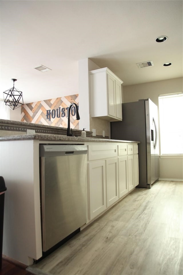 kitchen featuring appliances with stainless steel finishes, light wood-type flooring, and white cabinetry