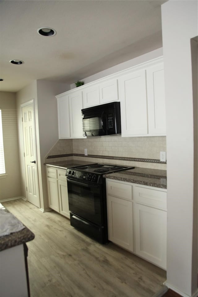 kitchen with tasteful backsplash, white cabinets, black appliances, light hardwood / wood-style flooring, and dark stone counters