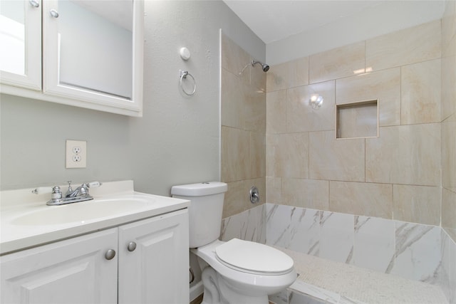 bathroom featuring a tile shower, vanity, and toilet