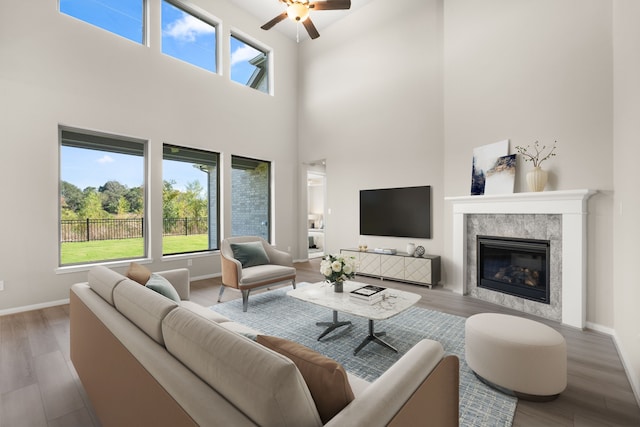 living room with ceiling fan, wood-type flooring, and a high ceiling