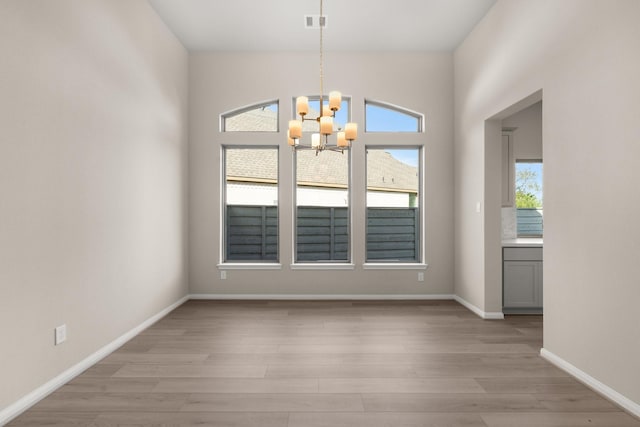 unfurnished dining area with light hardwood / wood-style floors and a notable chandelier