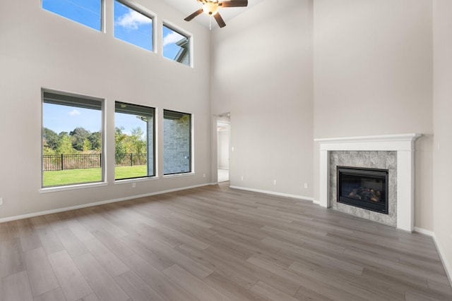 unfurnished living room with hardwood / wood-style floors, ceiling fan, and a high ceiling