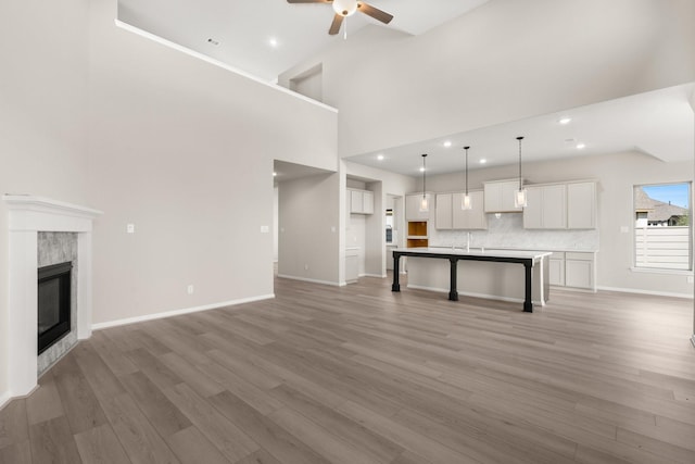 unfurnished living room featuring a towering ceiling, dark hardwood / wood-style floors, ceiling fan, and a premium fireplace