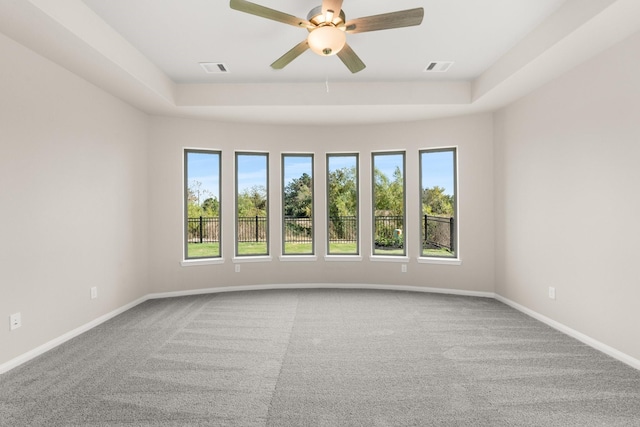 carpeted empty room featuring a raised ceiling and ceiling fan