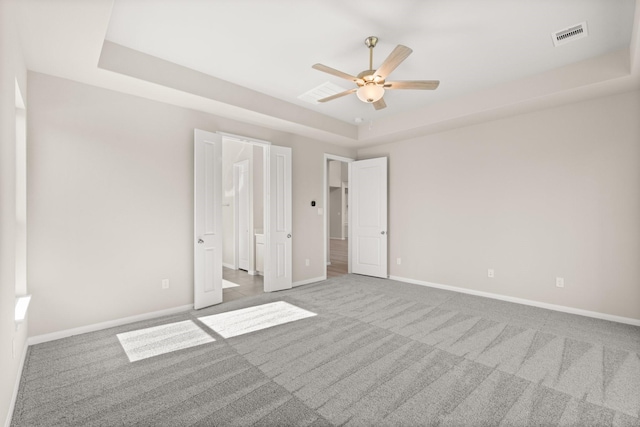 unfurnished bedroom featuring carpet, a raised ceiling, and ceiling fan